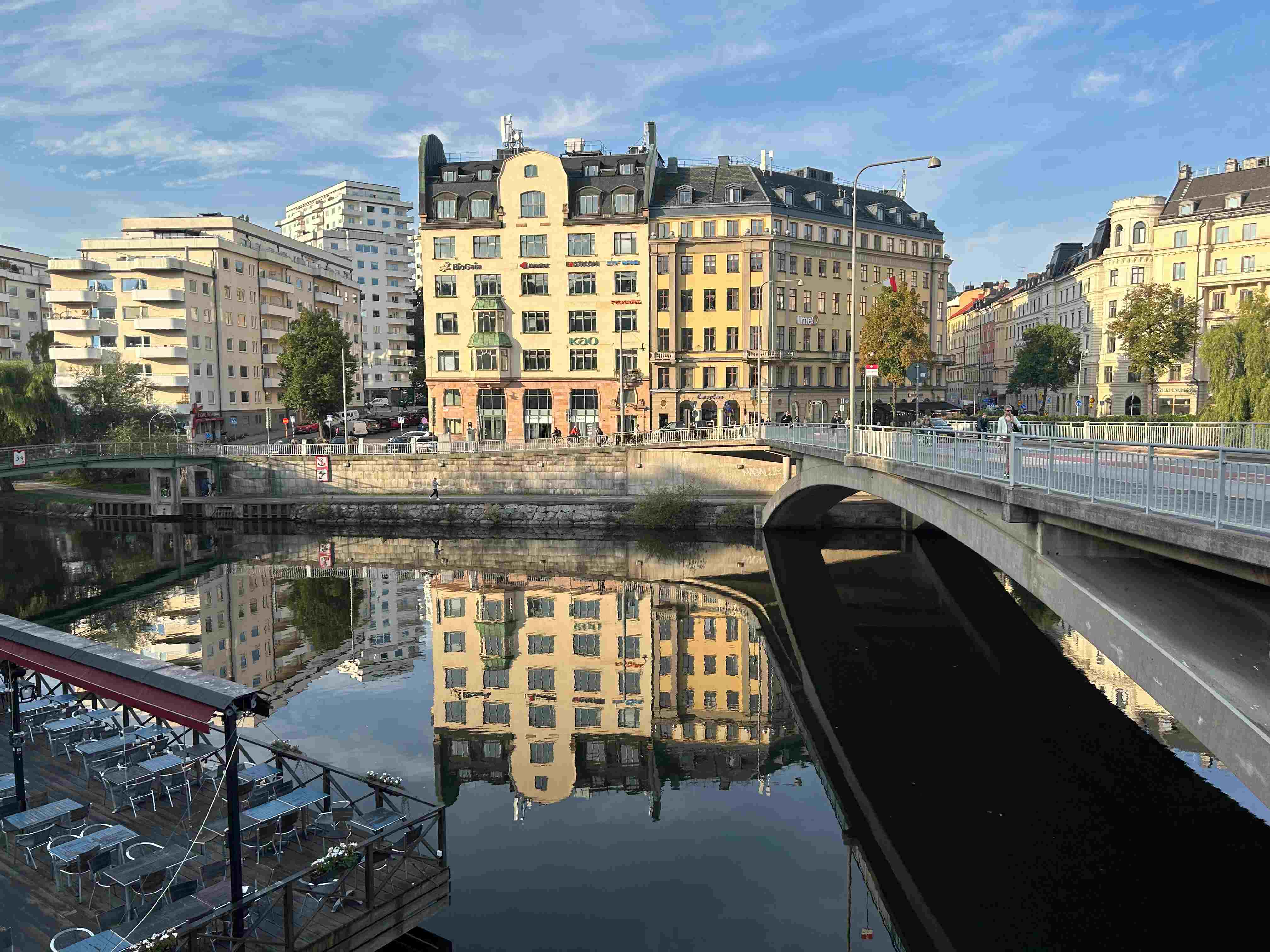 A bridge over a body of water with the Barker Brettell Sweden Office building in the background